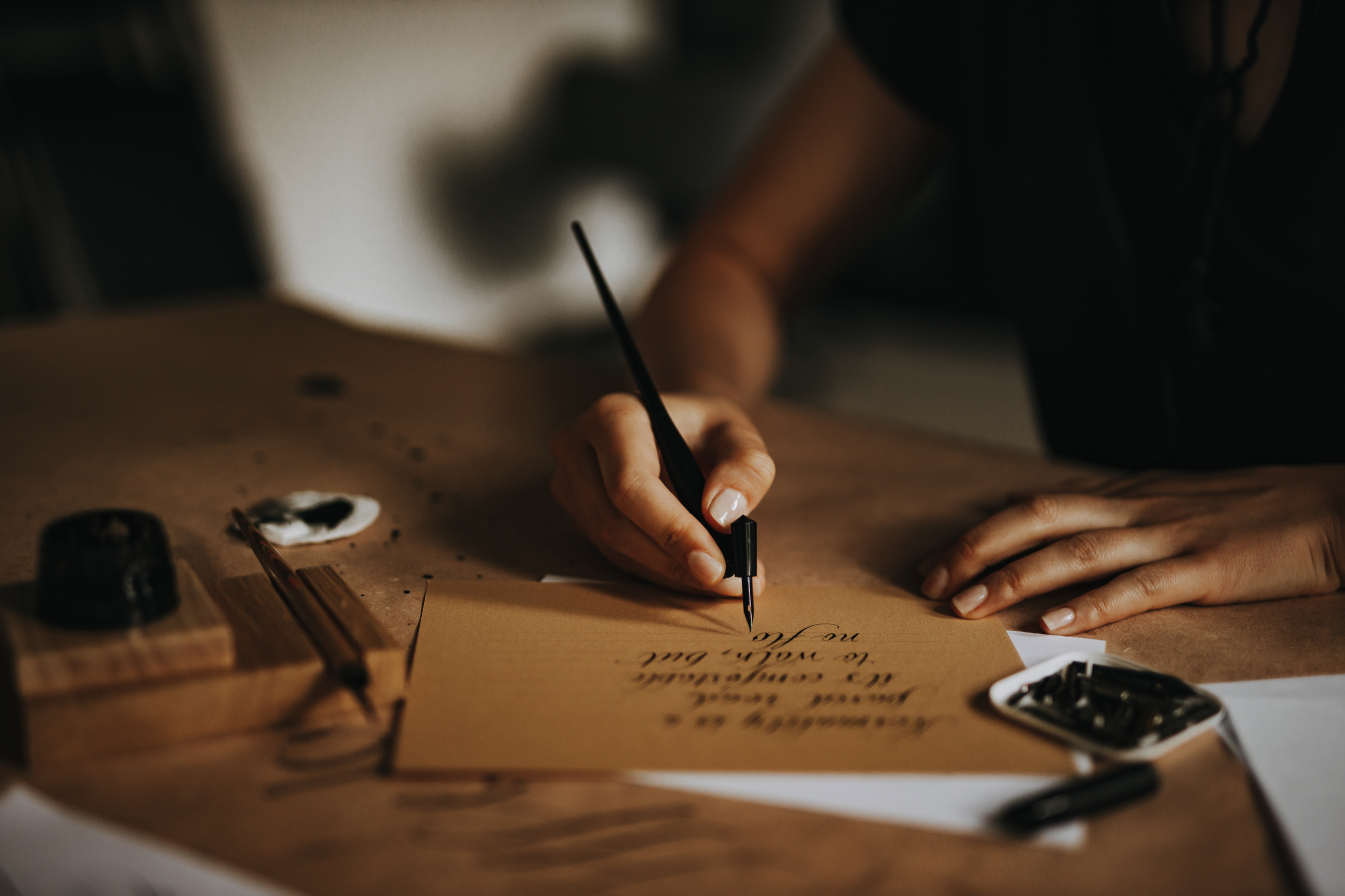 Calligrapher writing a letter with fountain pen on parchment.